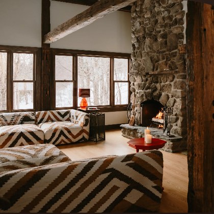 The great room at Mabel&rsquo;s Rest, with a stone fireplace and open timber beams